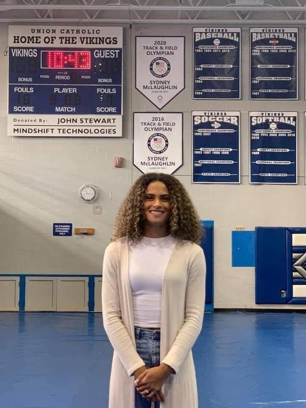 Two-time Olympic gold medalist Sydney McLaughlin poses for a photograph under her banners during a post-Olympic visit to her alma mater, Union Catholic Regional High School. (Photo courtesy of Jim Lambert/Union Catholic Regional High School)