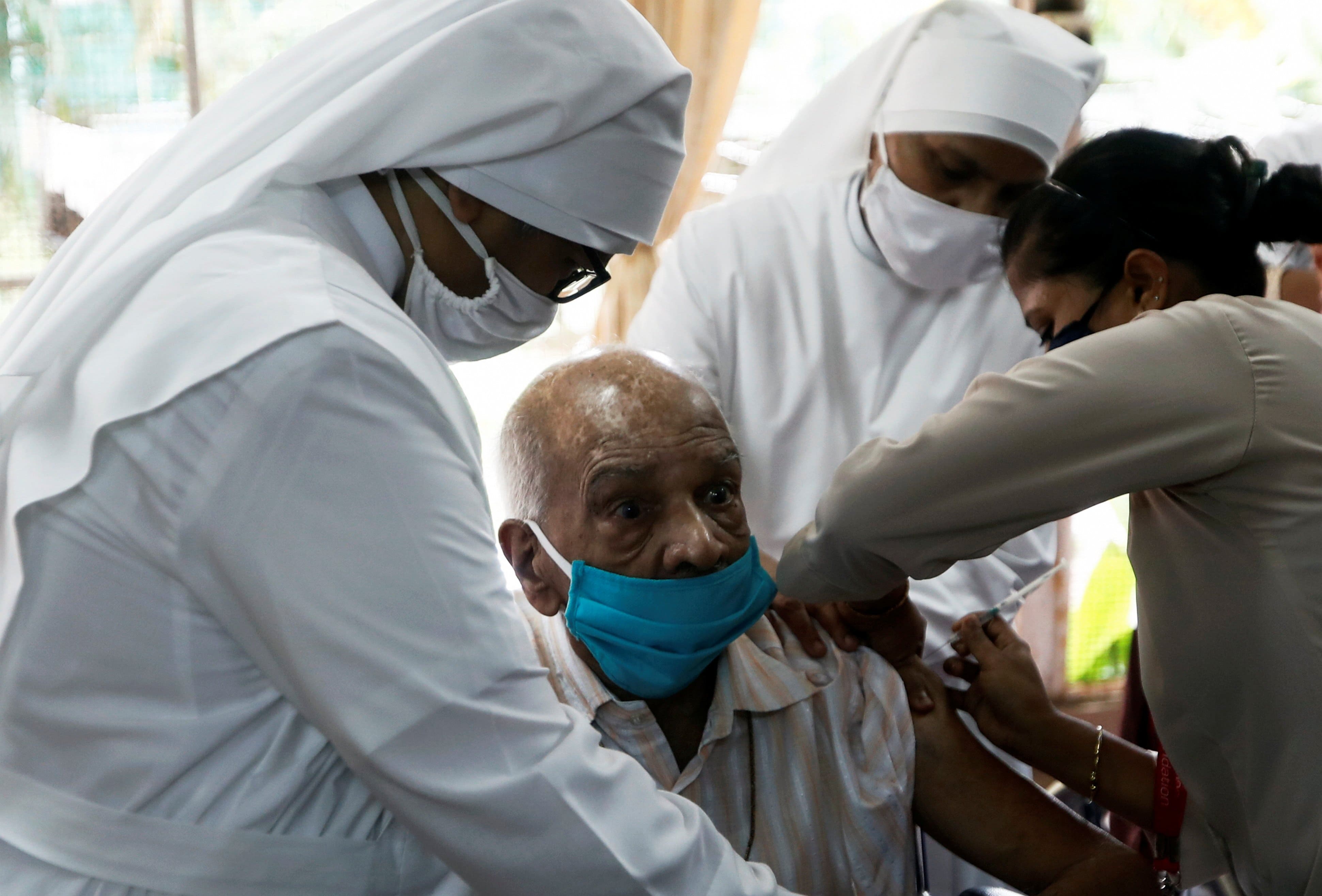 Nuns hold an elderly man as he receives a dose of the COVAXIN vaccine at a home for elderly in Mumbai, India, Aug. 2, 2021. The COVID-19 vaccine is manufactured by Bharat Biotech. (CNS photo/Francis Mascarenhas, Reuters)