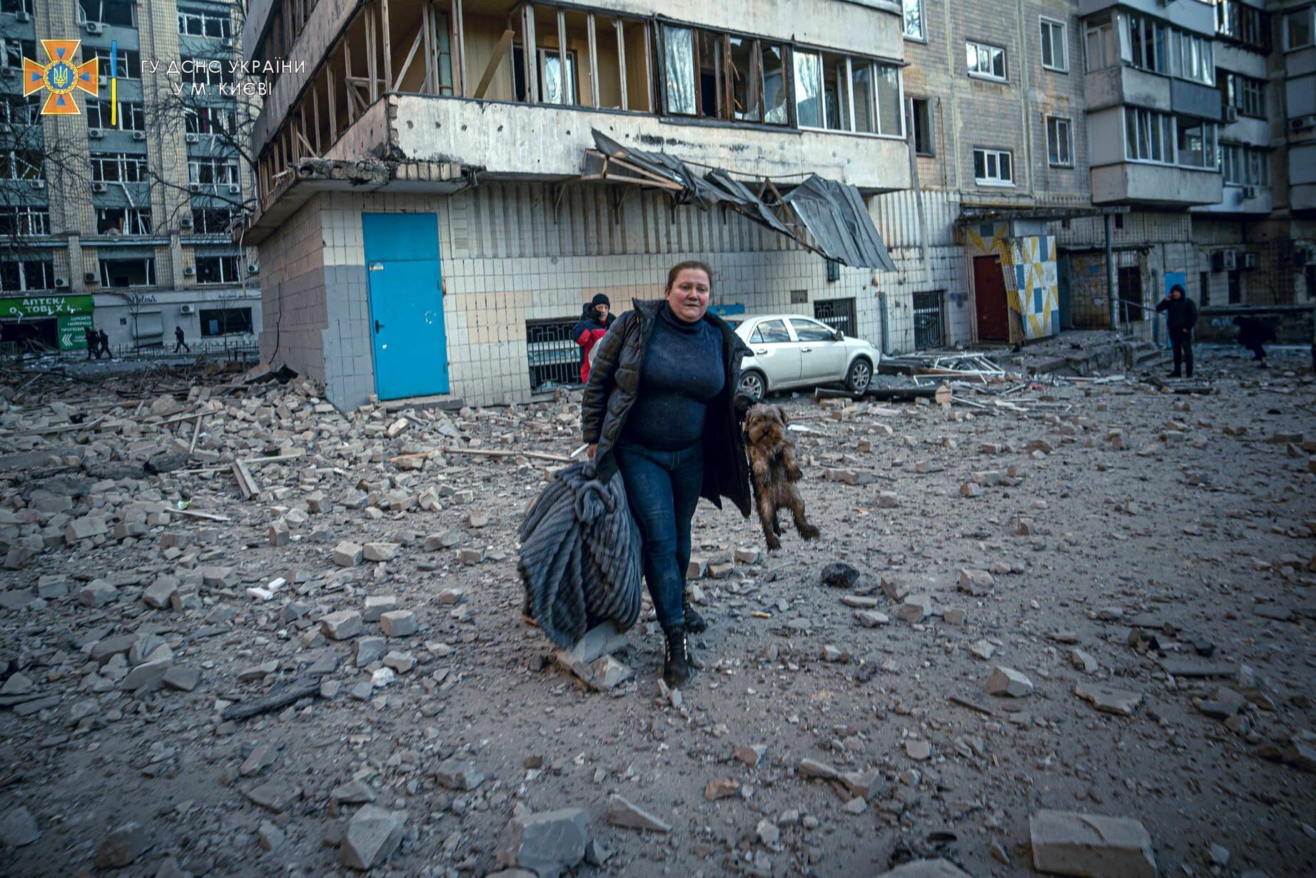 A woman carrying her dog evacuates from a residential building damaged by Russian shelling in Kyiv, Ukraine, March 16, 2022. (CNS photo/State Emergency Service of Ukraine handout via Reuters)