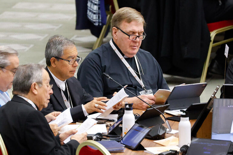 Cardinal Joseph W. Tobin of Newark, NJ, right, and other members of the assembly of the Synod of Bishops pray before a working session in the Vatican's Paul VI Audience Hall Oct. 26, 2023. (CNS photo/Lola Gomez)