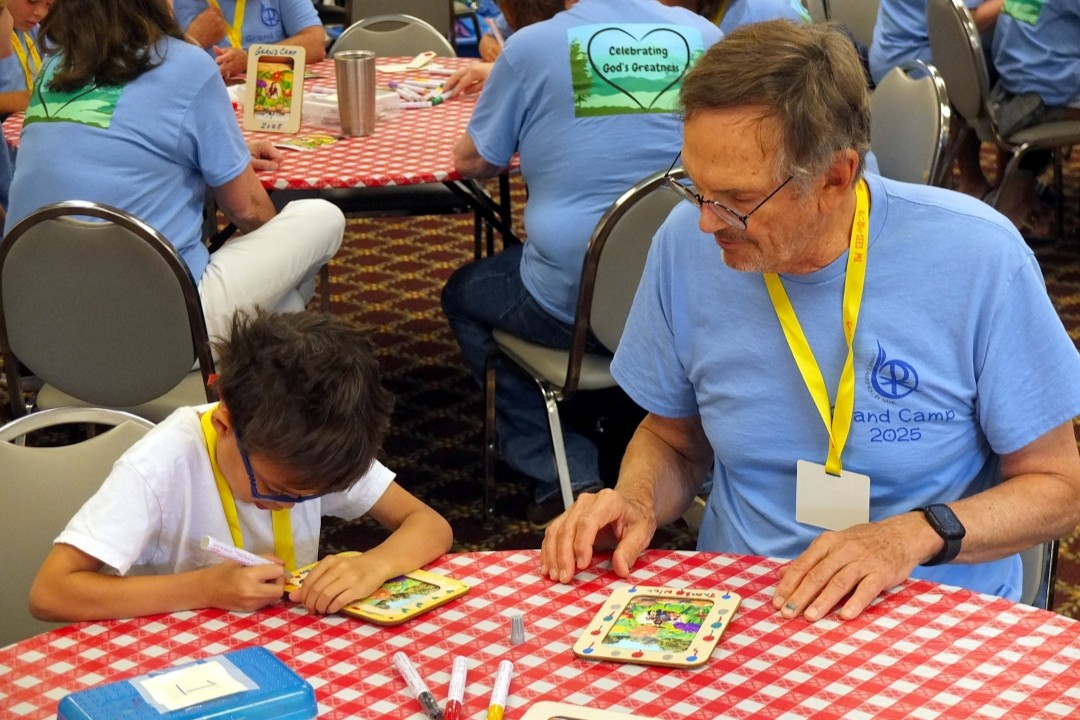 Grandfather and child work on an art project at Grand Camp