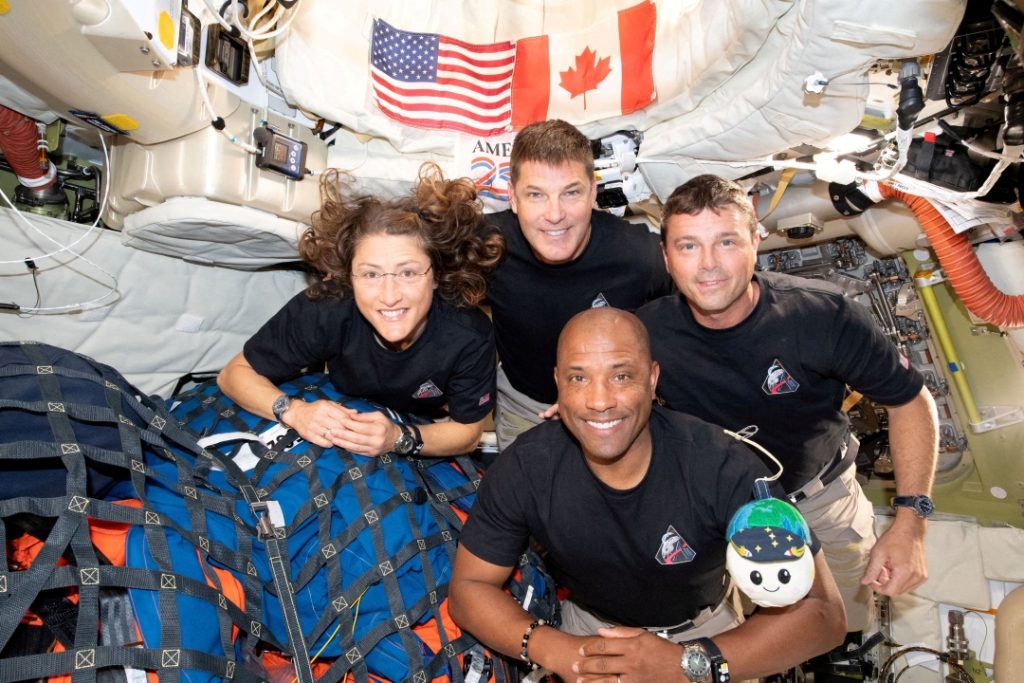 The Artemis II crew -- NASA astronaut Christina Koch, Canadian Space Agency astronaut Jeremy Hansen and NASA astronauts commander Reid Wiseman and pilot Victor Glover -- poses for a group photo April 6, 2026, inside the Orion spacecraft on their way home following a flyby of the far side of the moon.